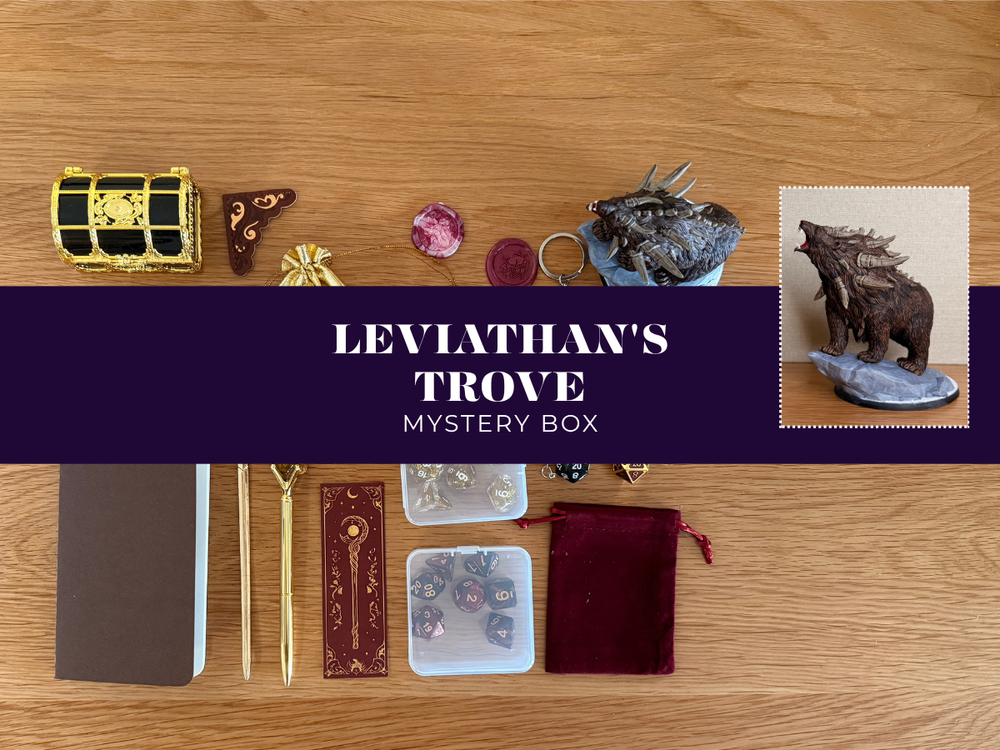 Leviathan's Trove Mystery Box contents arranged on a wooden tabletop, including a small gold-and-black treasure chest, crystals, a dark metallic figurine, dice, a notebook, rods, a velvet pouch, and a central purple banner reading 'LEVIATHAN'S TROVE MYSTERY BOX'.